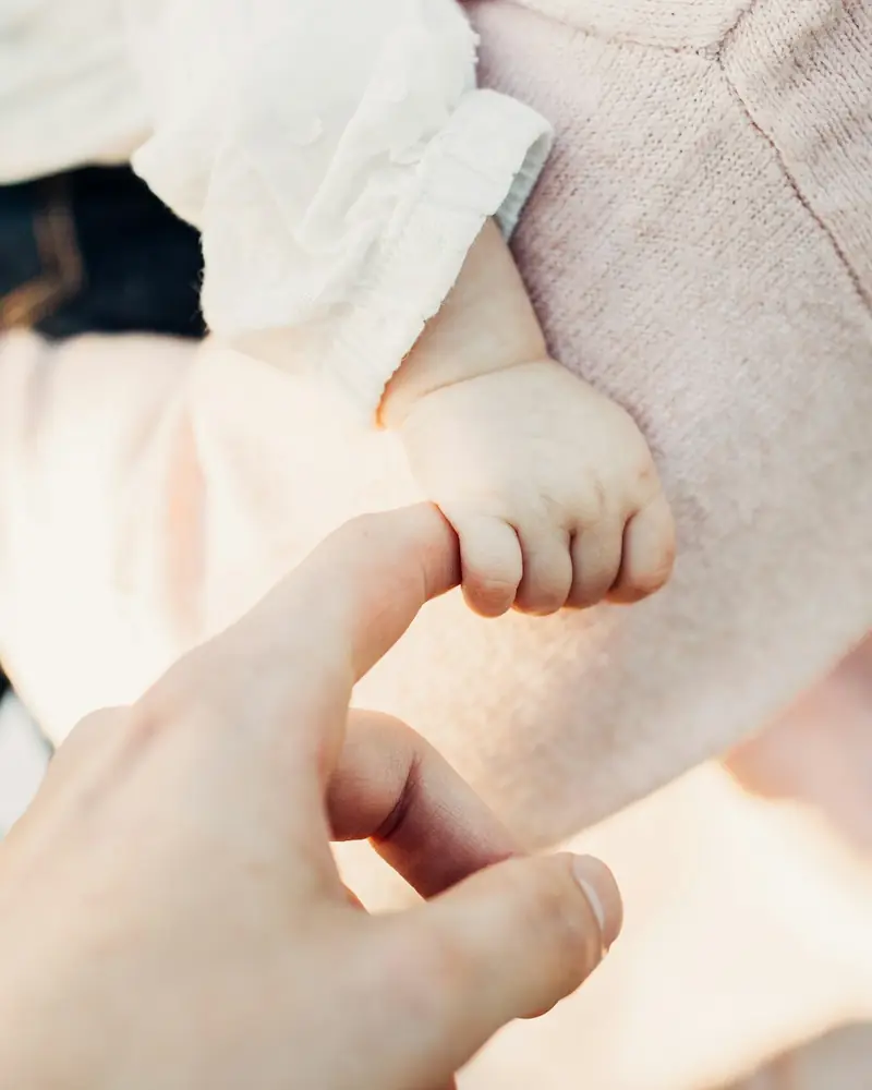 En liten babyhånd som holder rundt en voksen finger.